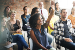 group of people sitting with one women raising her hand