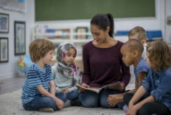 children and an adult sitting on the floor reading